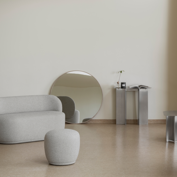 Modern living room featuring a gray sofa, round mirror, and sleek metallic furniture.