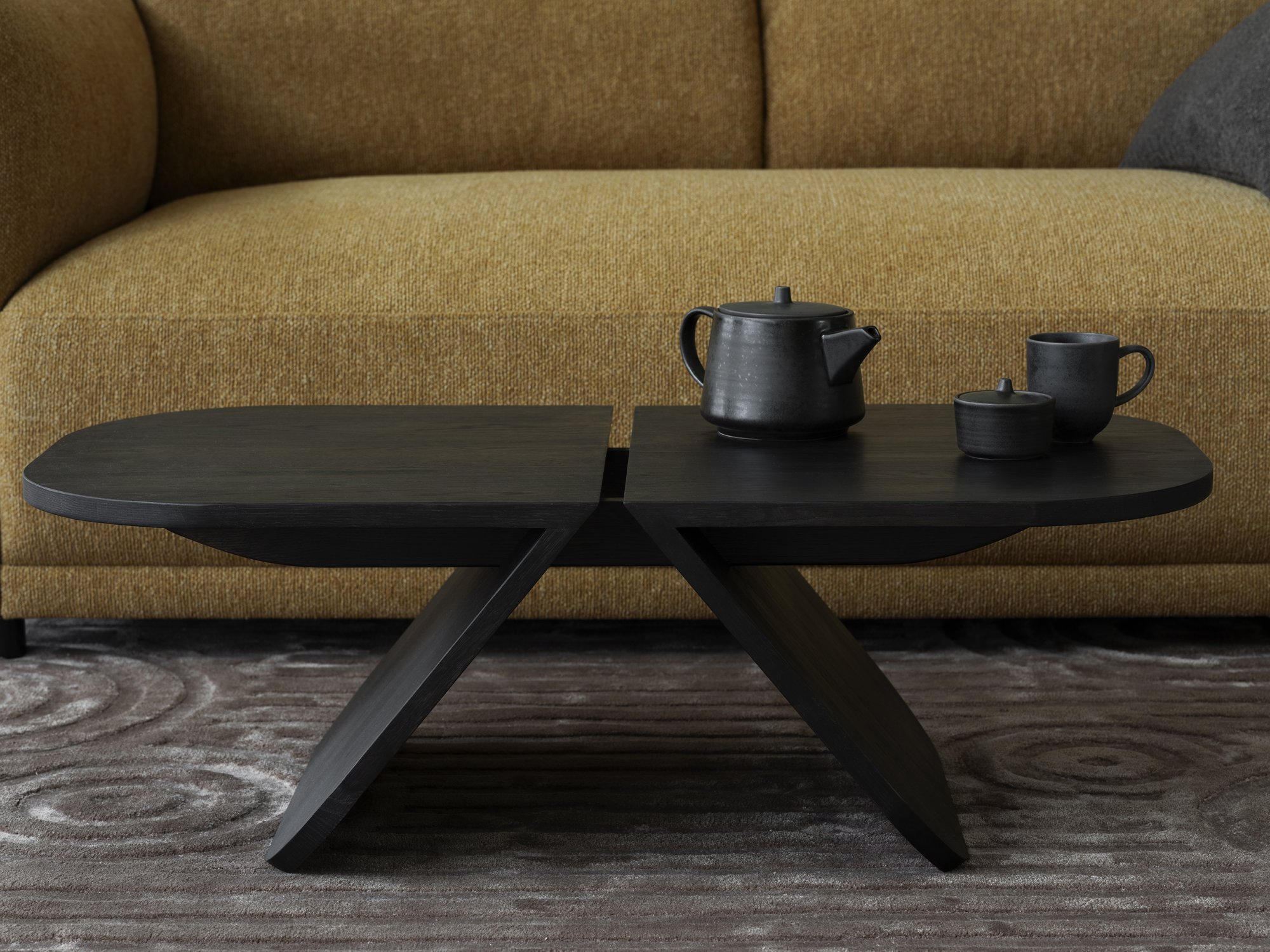 Stylish black coffee table with teapot and cups, set against a cozy yellow sofa.