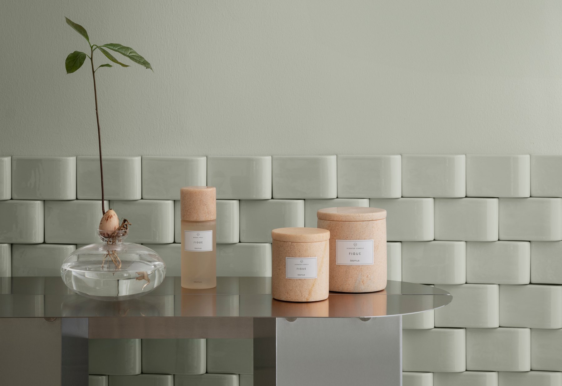 Elegant skincare products on a modern table against a pale green wall.