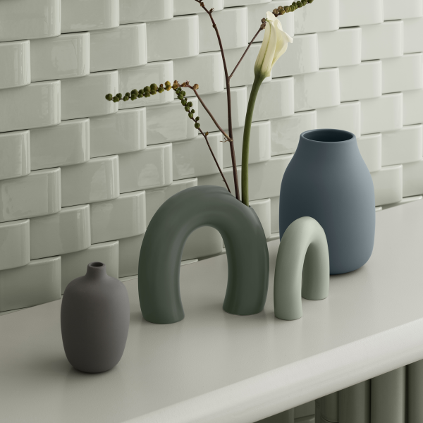 Decorative ceramic vases in soft colors displayed against a textured tile background.