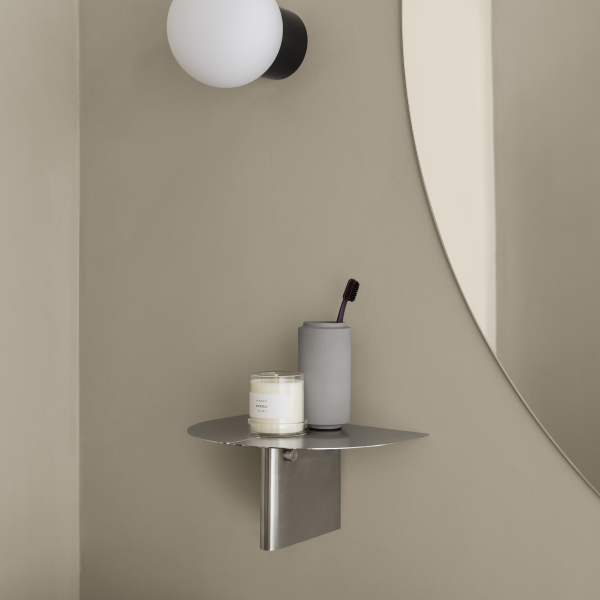 Sleek bathroom shelf with candle and toothbrush holder against a neutral wall.