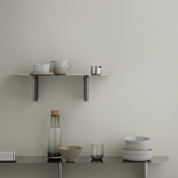 Minimalist kitchen shelf with modern ceramics and glassware against a neutral wall.