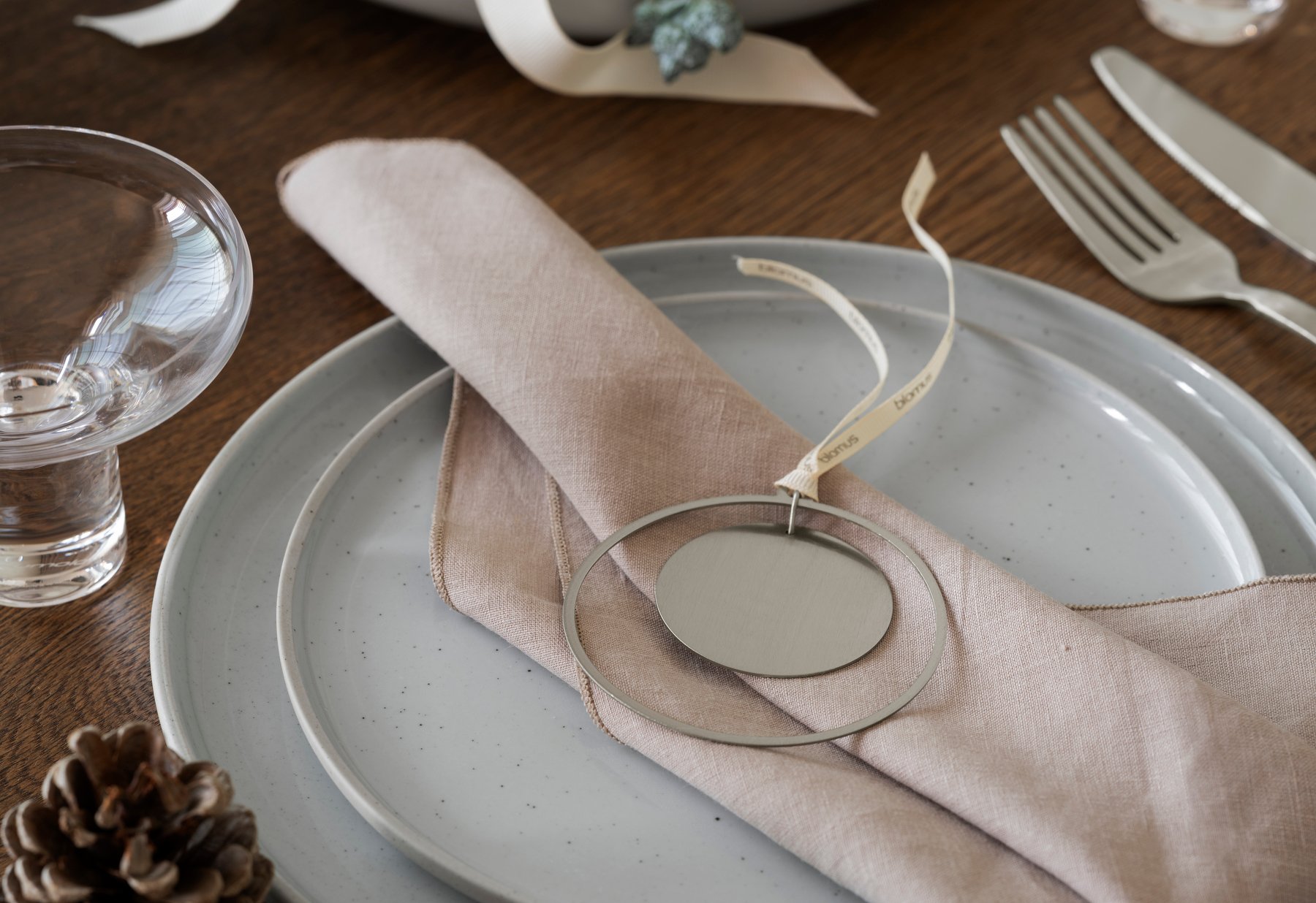 Stylish table setting with a beige napkin, metal tag, and rustic dishware.