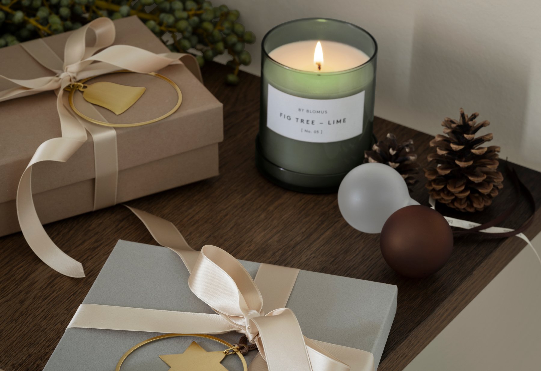 Elegant holiday setup featuring wrapped gifts, a scented candle, and decorative accents.