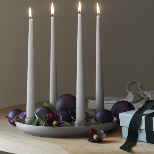 Elegant candle arrangement with purple spheres and flowers on a wooden table.