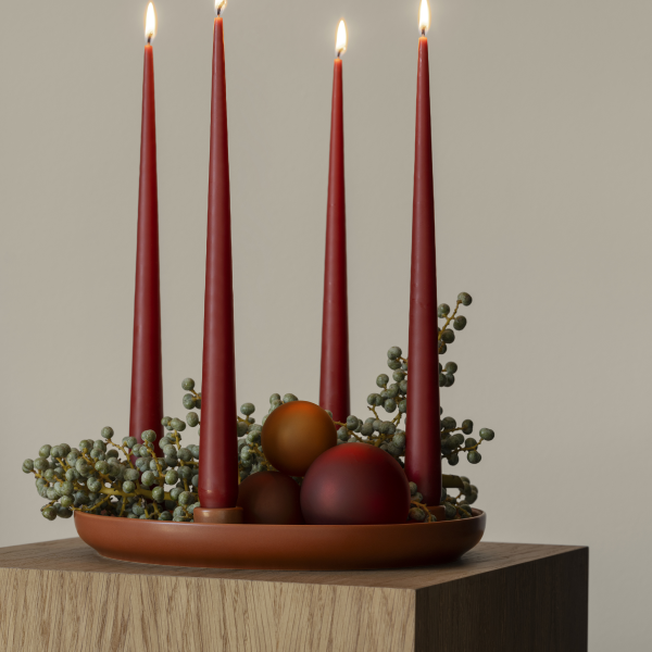 Elegant holiday centerpiece with red candles and decorative orbs on a wooden table.