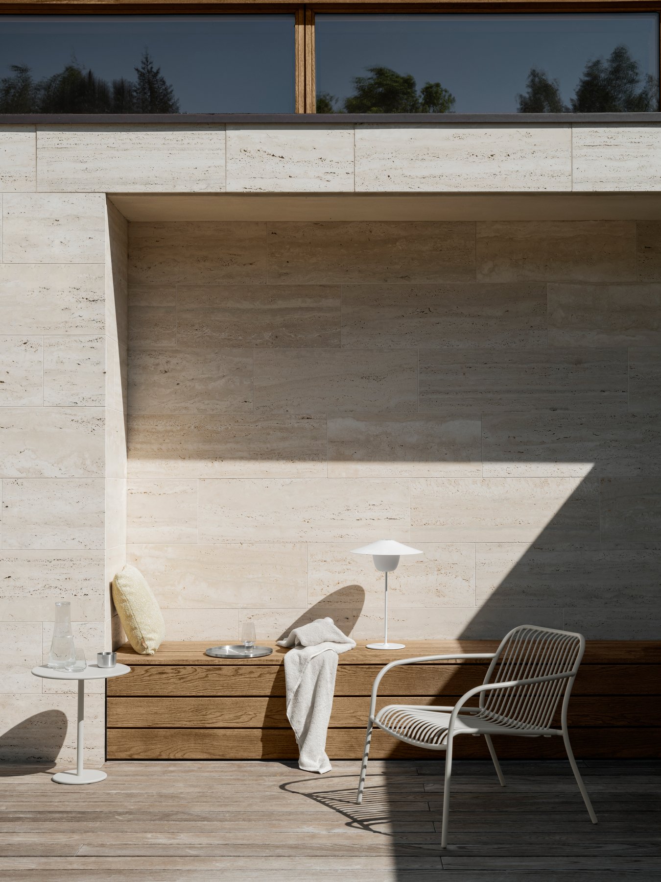 Modern outdoor seating area with minimalist design, natural stone walls, and soft lighting.