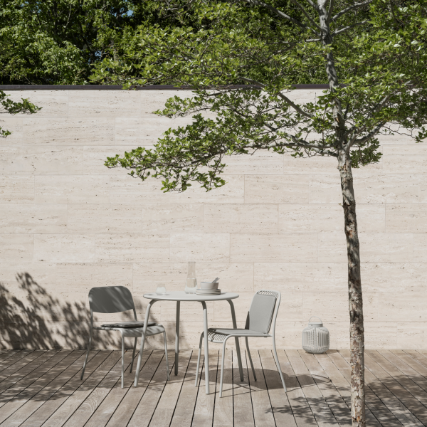 Modern outdoor dining area with a table and chairs surrounded by greenery.