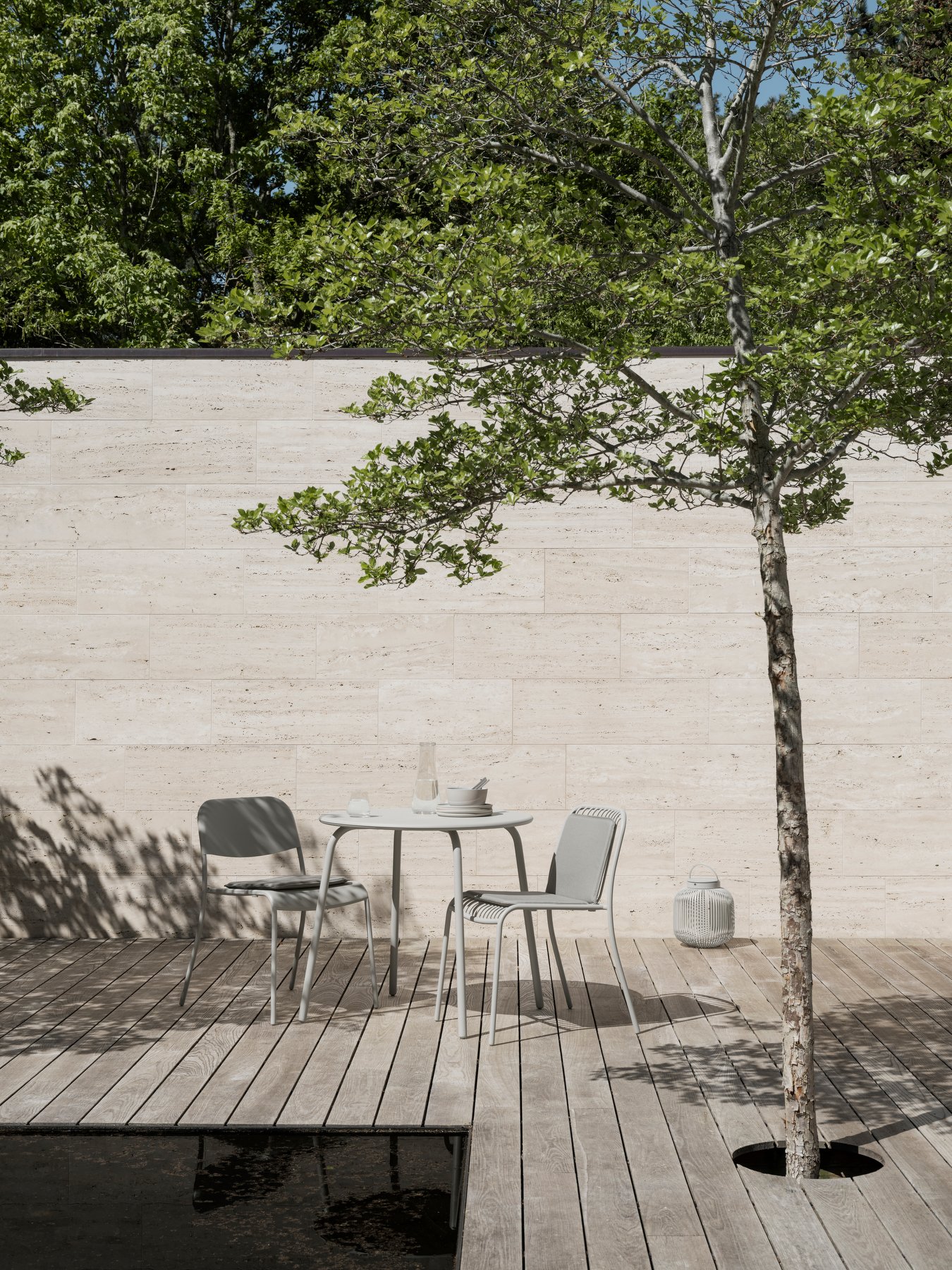 Modern outdoor dining area with a table and chairs surrounded by greenery.