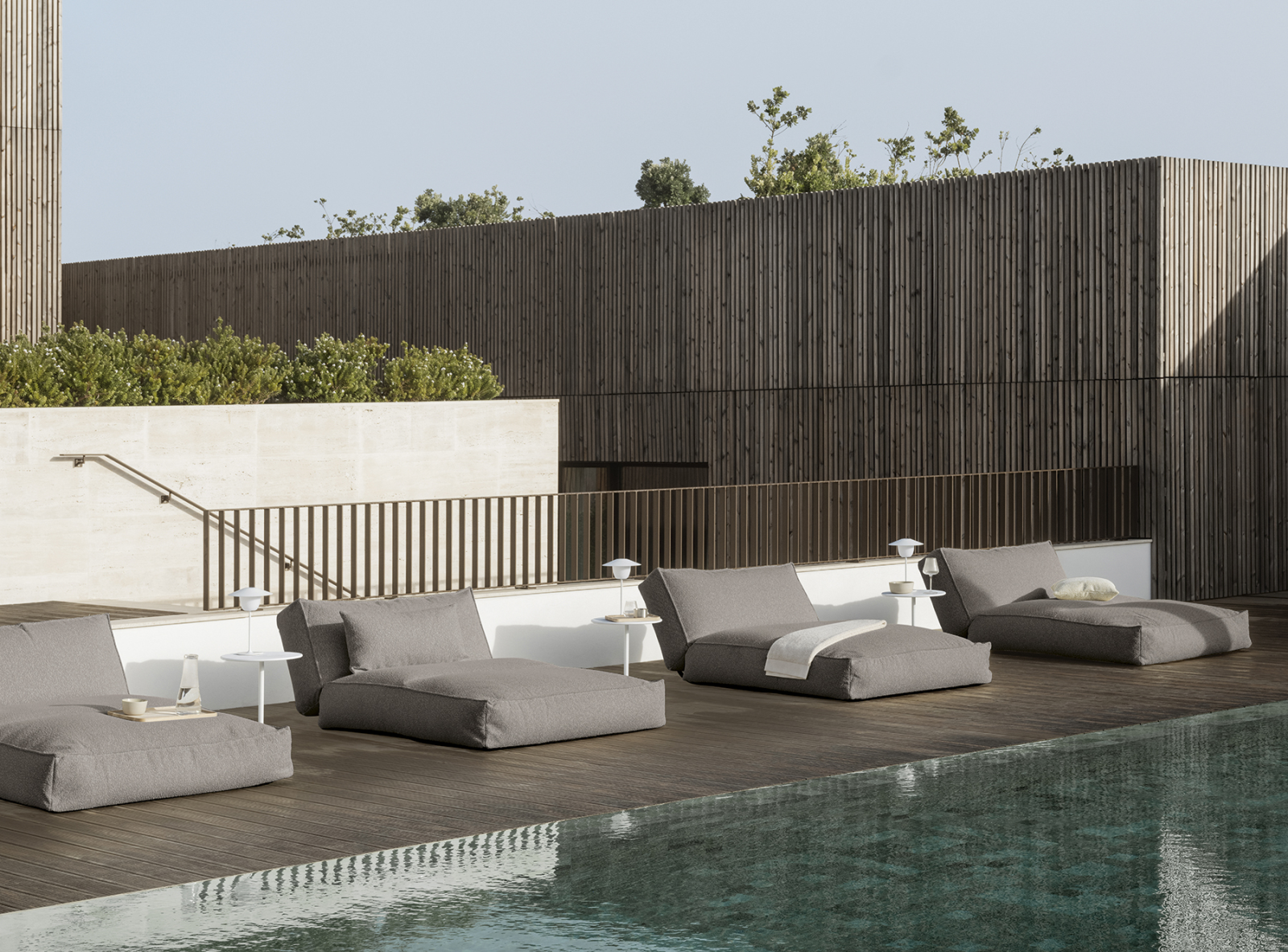 Modern outdoor lounge area with stylish cushions beside a serene pool.