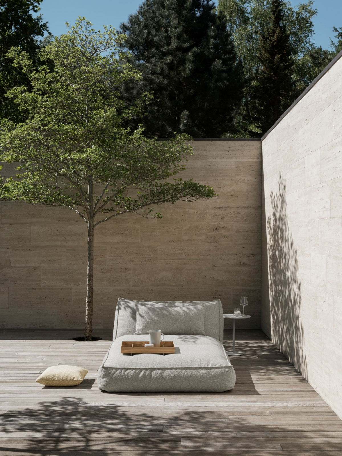 Cozy outdoor lounge area with a tree and minimalist decor in a serene setting.