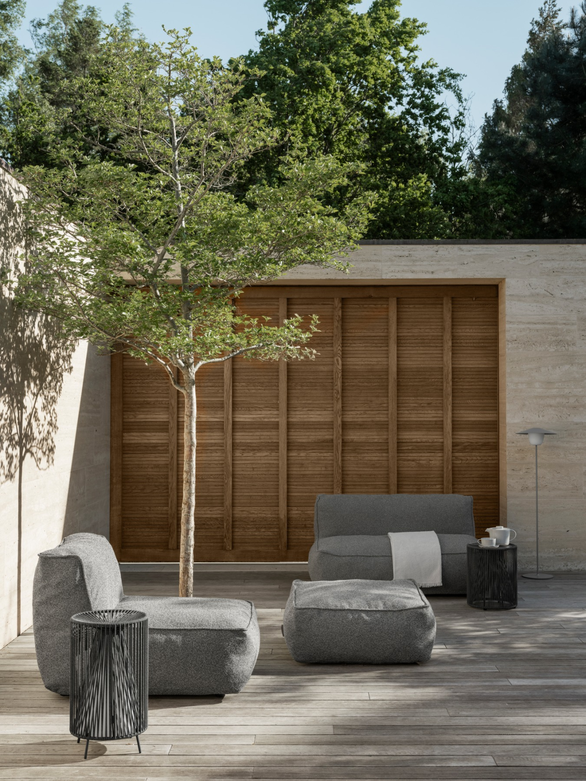 Stylish outdoor seating area featuring plush furniture and a tree in a serene setting.